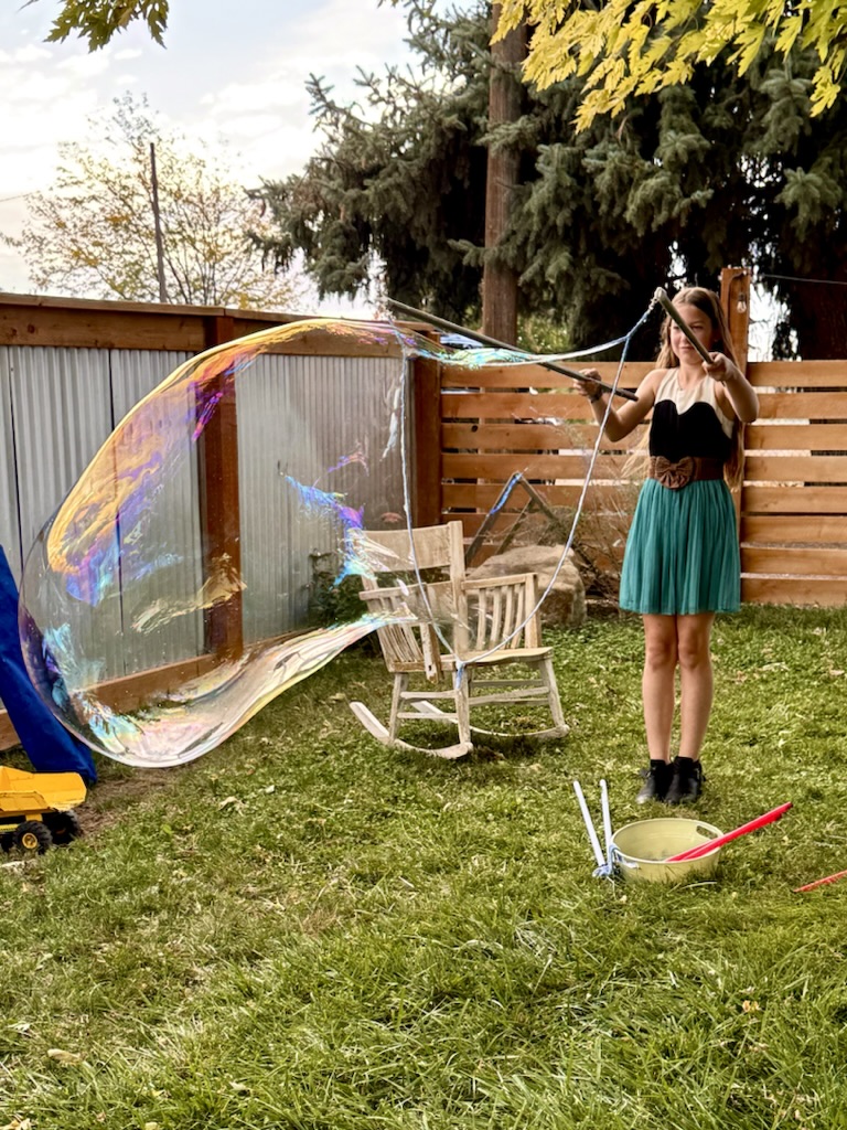 A guest making a giant rainbow bubble with a long wand