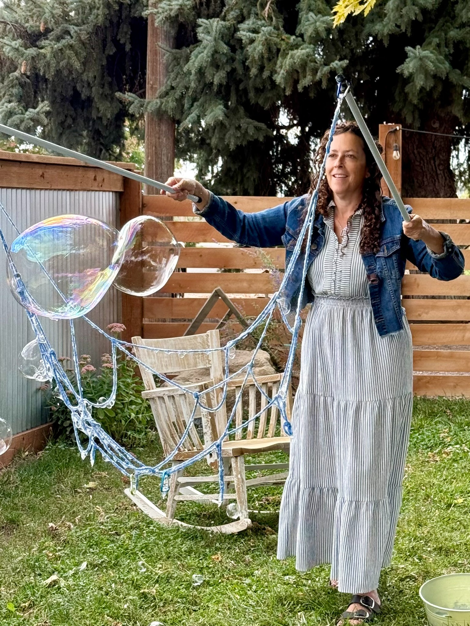 Jen creating colorful bubbles with two large wands