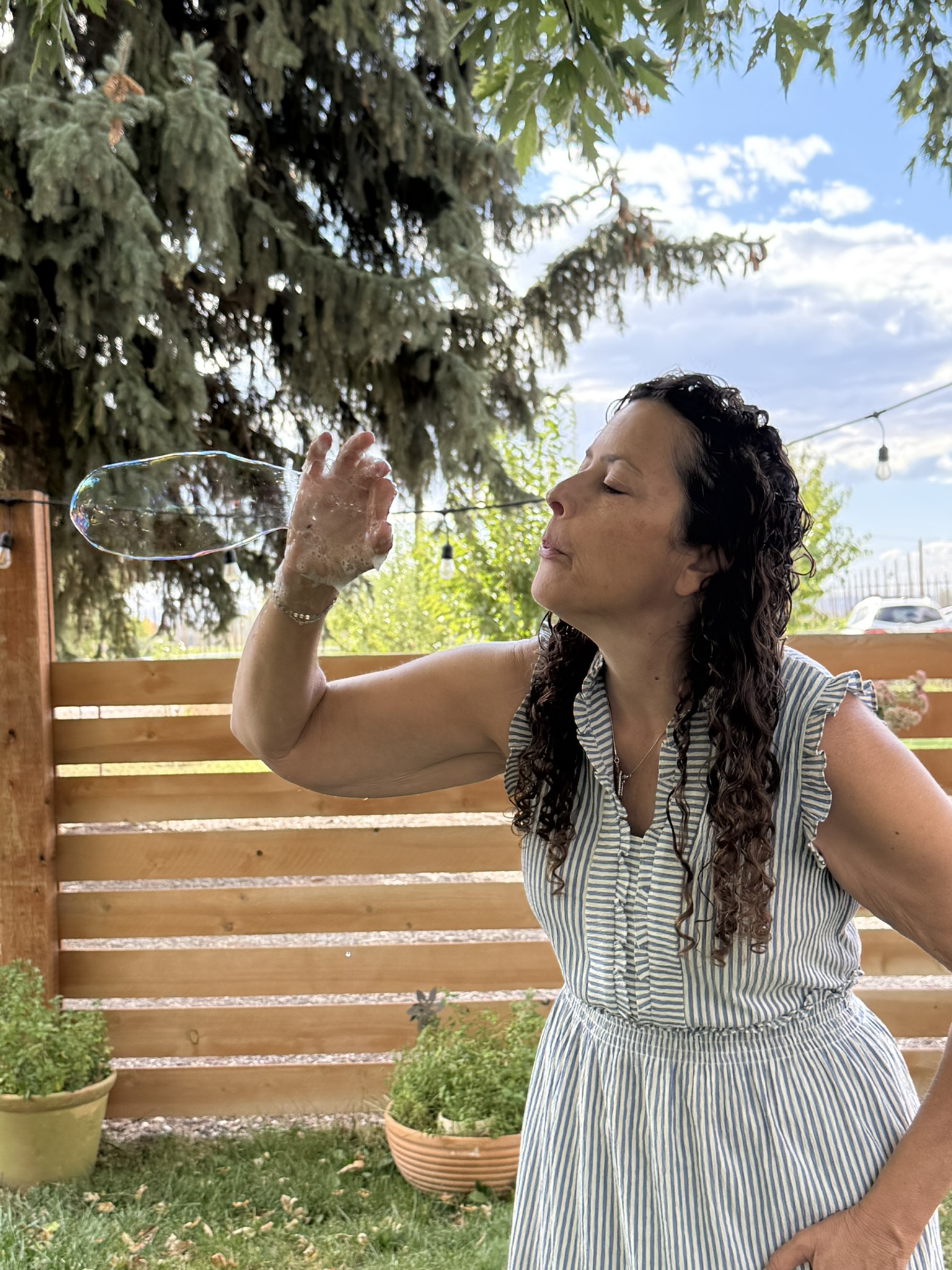 Jen smiling as she plays with a small floating bubble